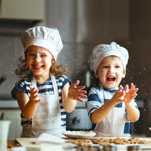 Toddlers having fun in the kitchen clapping hands.