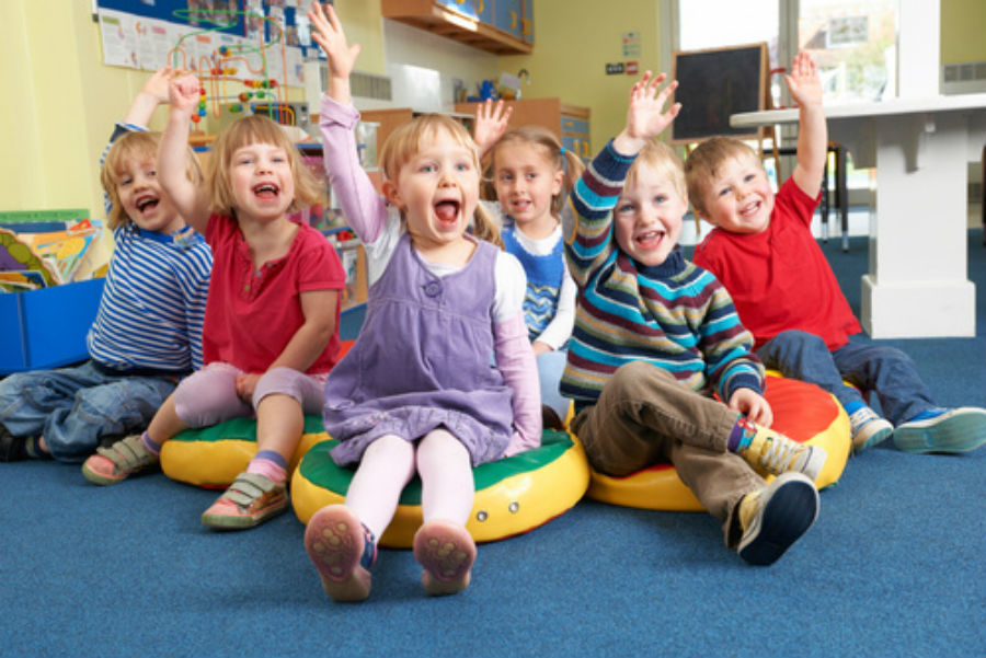 Happy children sitting in preschool and child care that started.
