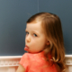 Child facing wall and turning backwards with tongue out to show disrespect.