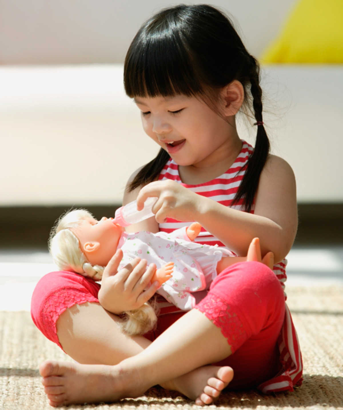 Only child smiling and playing with a doll.
